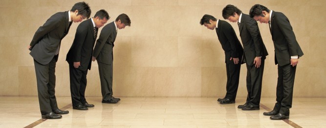 Two groups of businessmen bowing to each other, side view